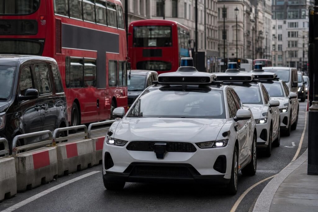 Önvezető taxikra váró, zsúfolt londoni utca piros buszokkal
