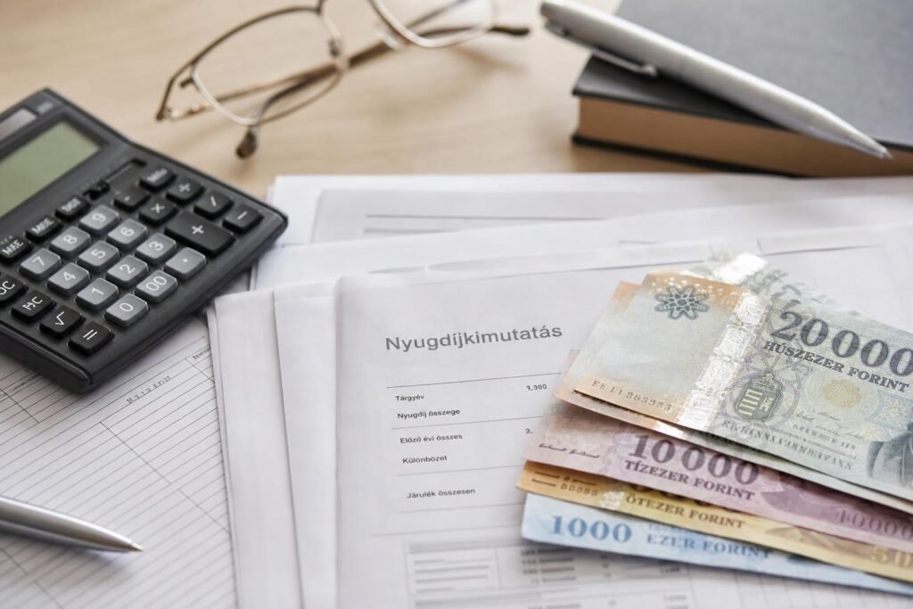Nyugdíjemeléshez kapcsolódó iratok és forintbankjegyek egy asztalon